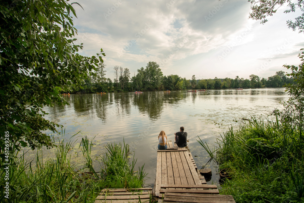 A couple sits on a wooden pier on the Moscow River (old stream)