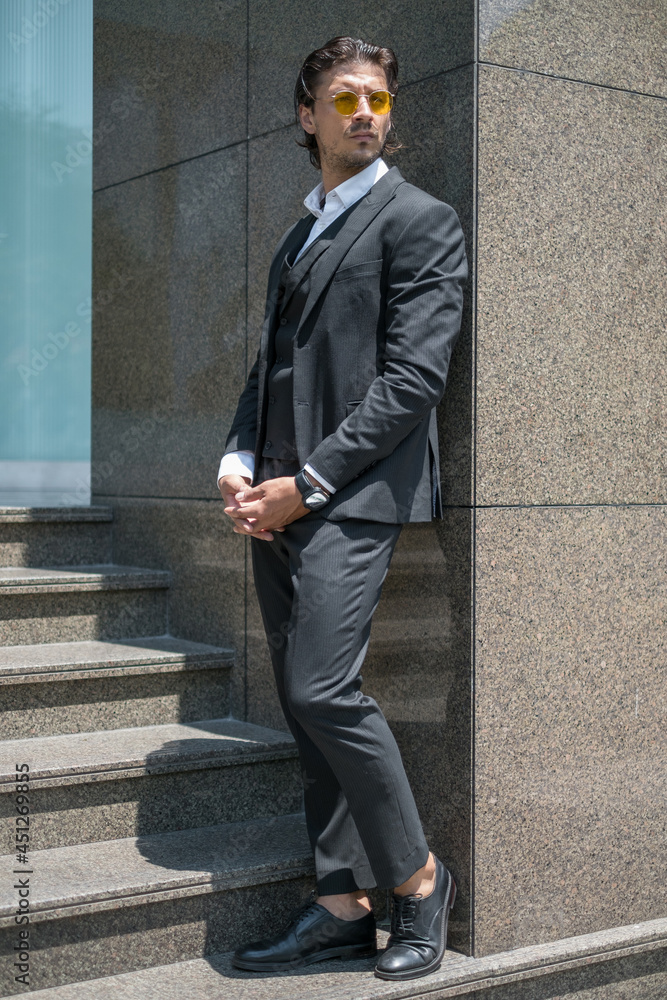 Handsome man in black formal suit and yellow sunglasses standing on the stairs. High quality photo Handsome man in black formal suit and yellow sunglasses standing on the stairs. High quality photo