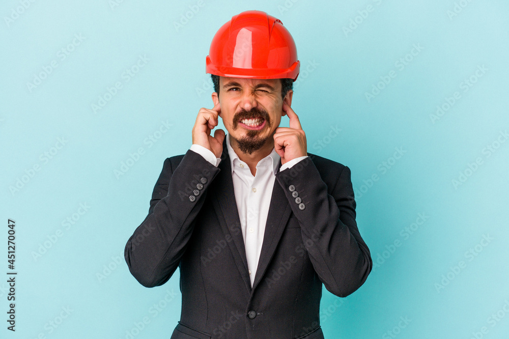 Young architect caucasian man isolated on blue background covering ears with hands. Young architect caucasian man isolated on blue background covering ears with hands.