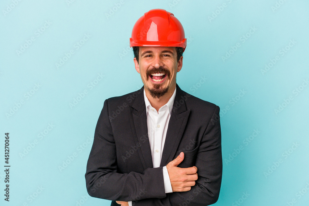 Young architect caucasian man isolated on blue background laughing and having fun. Young architect caucasian man isolated on blue background laughing and having fun.