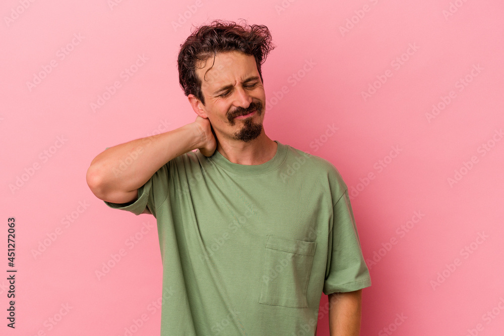 Young caucasian man isolated on pink background having a neck pain due to stress, massaging and touching it with hand. Young caucasian man isolated on pink background having a neck pain due to stress, massaging and touching it with hand.