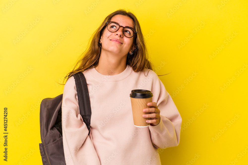 Young caucasian student woman holding coffee isolated on yellow background dreaming of achieving goals and purposes Young caucasian student woman holding coffee isolated on yellow background dreaming of achieving goals and purposes