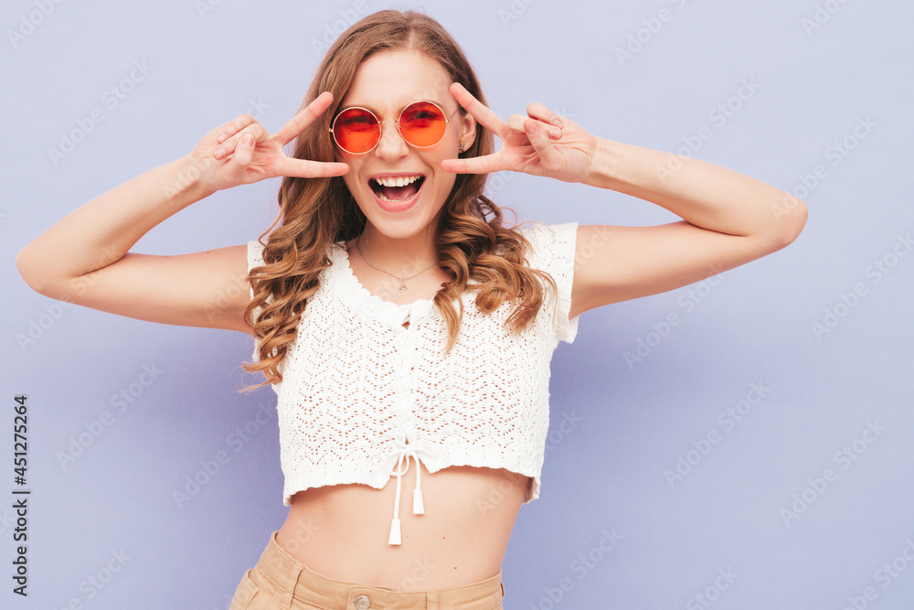 Young beautiful smiling female in trendy summer red white hipster overalls. Sexy carefree woman posing near purple wall in studio. Positive model having fun indoors Young beautiful smiling female in trendy summer red white hipster overalls. Sexy carefree woman posing near purple wall in studio. Positive model having fun indoors