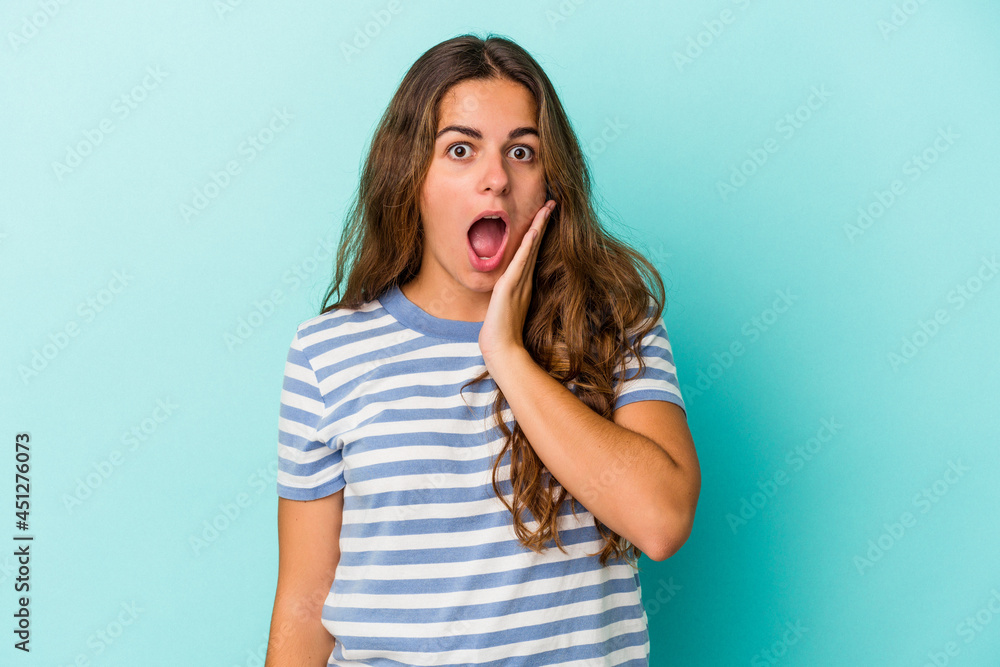 Young caucasian woman isolated on blue background shouts loud, keeps eyes opened and hands tense. Young caucasian woman isolated on blue background shouts loud, keeps eyes opened and hands tense.