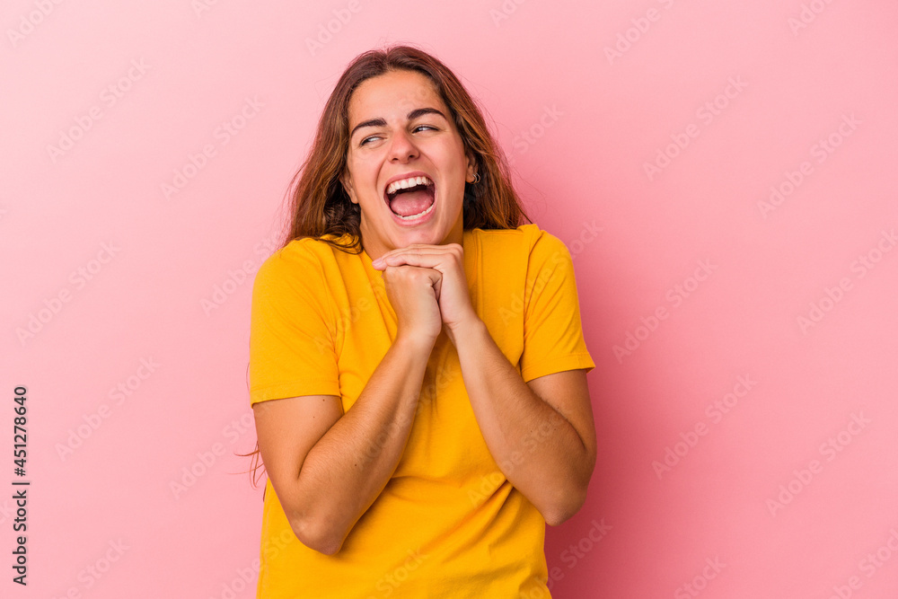 Young caucasian woman isolated on pink background keeps hands under chin, is looking happily aside. Young caucasian woman isolated on pink background keeps hands under chin, is looking happily aside.