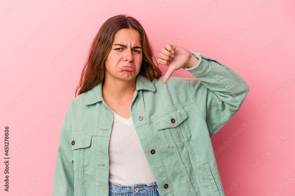 Young caucasian woman isolated on pink background showing thumb down and expressing dislike. Young caucasian woman isolated on pink background showing thumb down and expressing dislike.