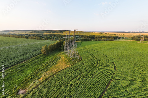 Transmission line in rural field. High-voltage tower for electrical grid in aerial view