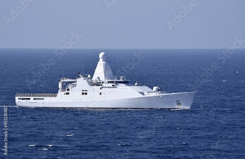 White ocean going patrol vessel equipped with sophisticated communications equipment in the dark blue ocean with blue sky in the background © skyf