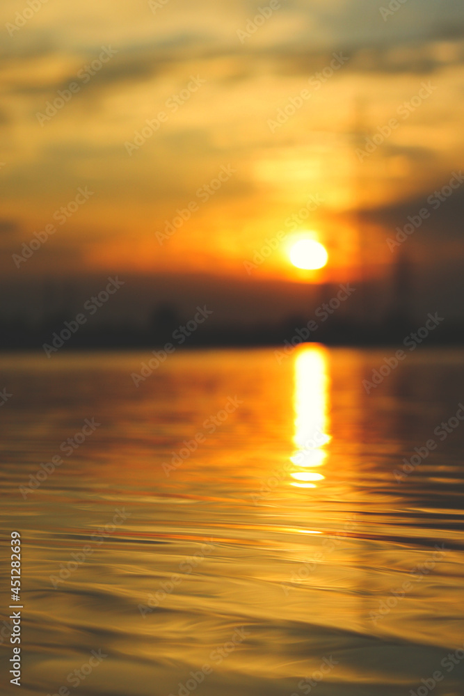Beautiful sunset near the water, the water is in focus and the background is blurred, vertically