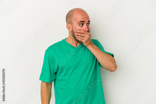 Young bald man isolated on white background thoughtful looking to a copy space covering mouth with hand. © Asier