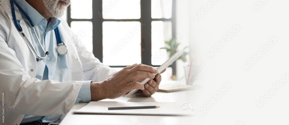 Cheerful mature doctor using digital tablet in clinic. Cheerful mature doctor using digital tablet in clinic.