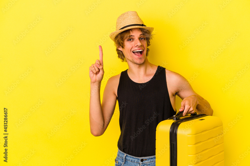 Young caucasian man with makeup going to travel isolated on yellow background showing number one with finger. Young caucasian man with makeup going to travel isolated on yellow background showing number one with finger.