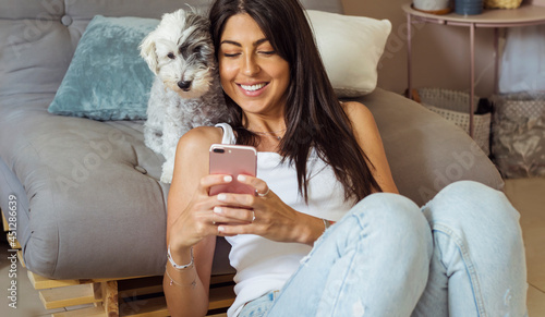 Bilde på lerret Beautiful  Smiling Woman Holding her Phone and Hugging with her Havanese Dog at