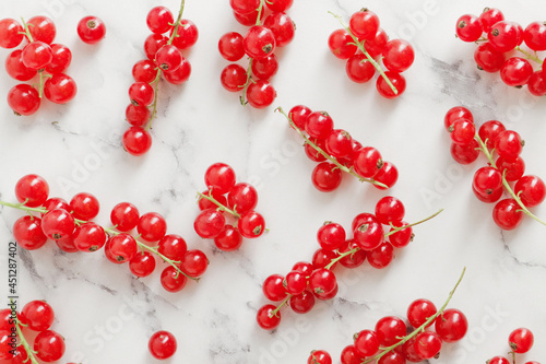 composition of ripe red currant berries on a textured marble background