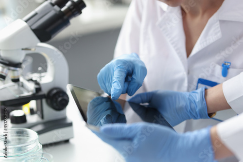 Scientists in sterile gloves hold tablet in laboratory closeup