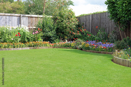 Canvas Print Pretty Colourful Flower Beds Bordering A Well Maintained Lawn.