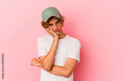 Young caucasian man with make up isolated on pink background who is bored, fatigued and need a relax day.