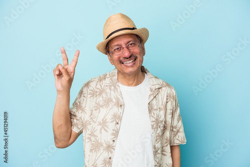 Senior indian man wearing summer clothes isolated on blue background Senior indian woman wearing a african costume isolated on white background joyful and carefree showing a peace symbol with fingers.