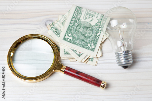 magnifier, light bulb and money on the table