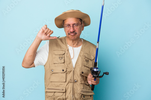 Senior indian fisherman holding rod isolated on blue background showing a dislike gesture, thumbs down. Disagreement concept.