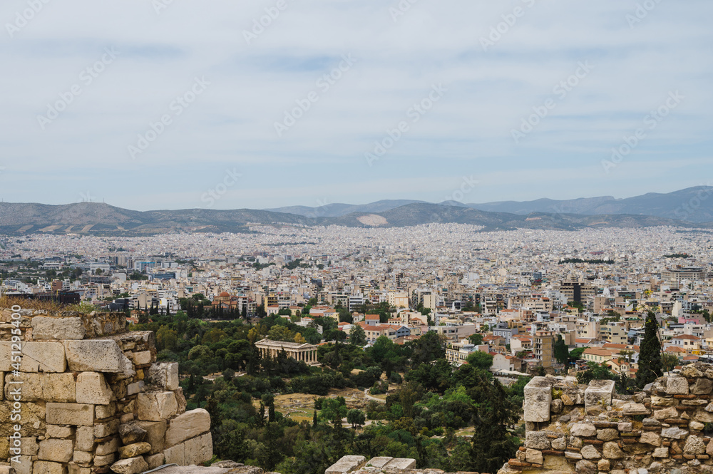 Cityscape of Athens at cloudy day. City near hills. Urban architecture in Europe. View from Acropolis hill of The Temple of Hephaestus. Ancient ruins.