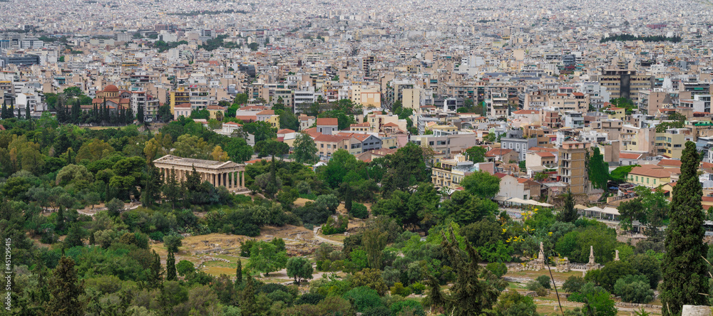 Cityscape of Athens at cloudy day. Urban architecture in Europe. View from Acropolis hill of The Temple of Hephaestus. Green trees.