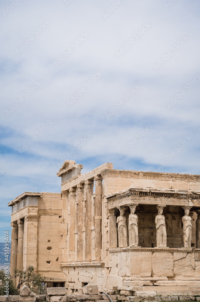 Remains of ancient marble temple on Acropolis hill in Athens, Greece. The Erechtheion, ancient Greek settlement. Cloudy sky. Nobody. Landmark of Athens.