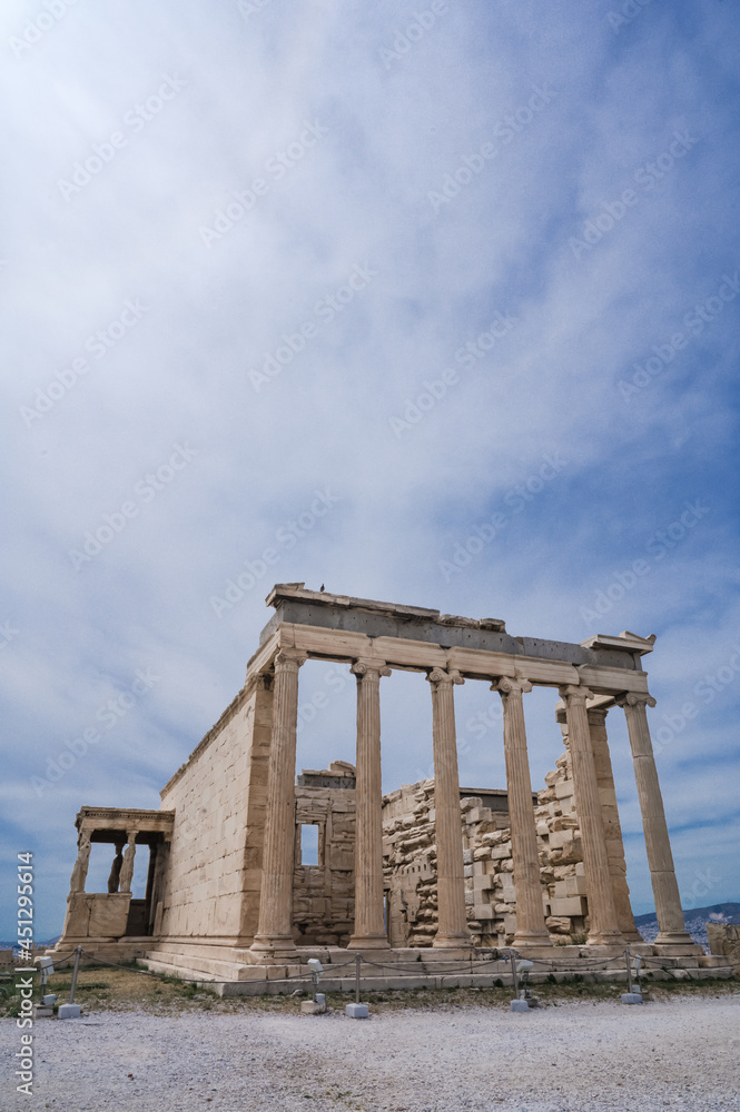 Remains of ancient marble temple on Acropolis hill in Athens, Greece. The Erechtheion, ancient Greek settlement. Cloudy sky. Nobody. Landmark of Athens.