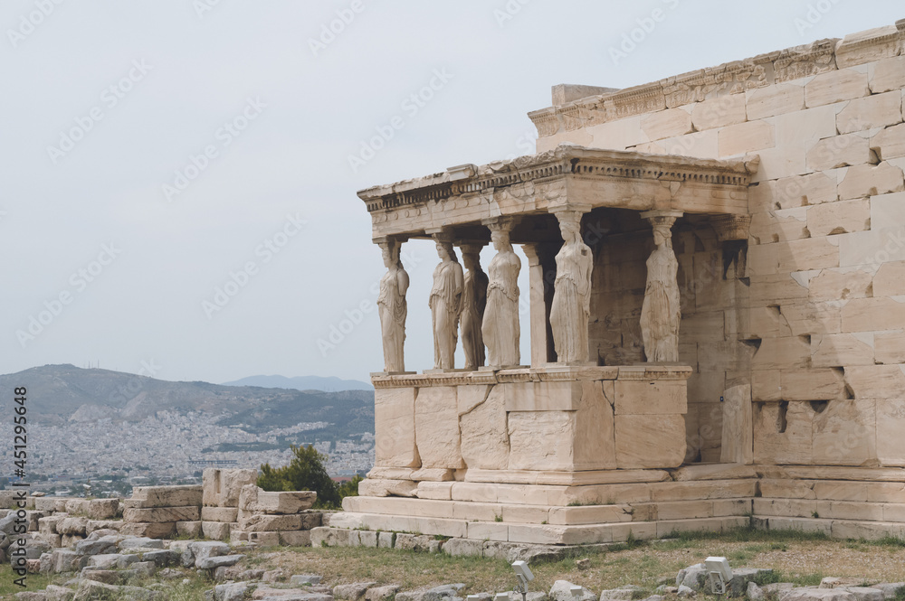 Ancient marble temple on Acropolis hill in Athens, Greece. Caryatids of the Erechtheion. Cloudy sky. Nobody. Landmark of Athens.