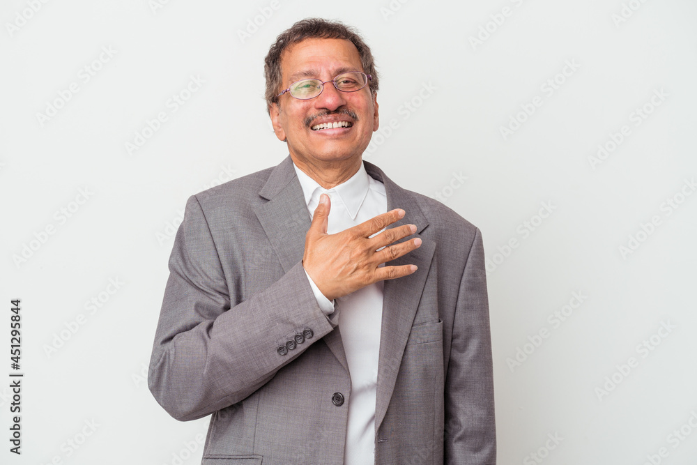 Middle aged indian business man isolated on white background laughs out loudly keeping hand on chest. Middle aged indian business man isolated on white background laughs out loudly keeping hand on chest.