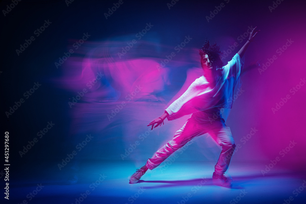 Colourful shot of dancing girl. Female dancer performer show expressive hip hop dance. Colored neon light, long exposure - obrazy, fototapety, plakaty 
