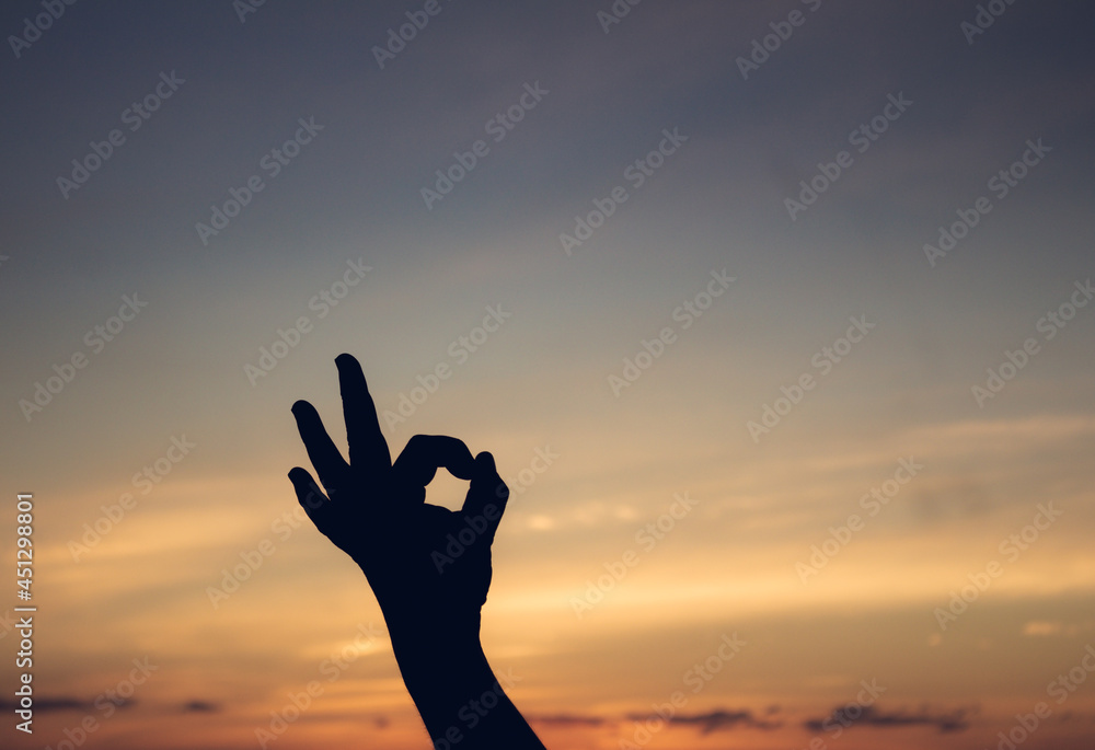 Beautiful sunset in the tropics with silhouettes of a man with his hands in a Buddhist position.