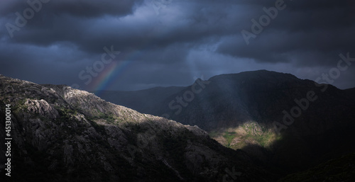 Bonita paisagem dramática nas montanhas com raio de luz nas nuvens e arco-íris