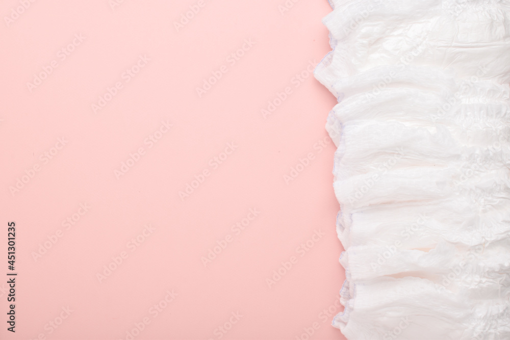 A large stack of disposable diaper panties on a pink background with a place to copy. top view, a place to copy. A large stack of disposable diaper panties on a pink background with a place to copy. top view, a place to copy.