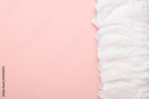 A large stack of disposable diaper panties on a pink background with a place to copy. top view, a place to copy.