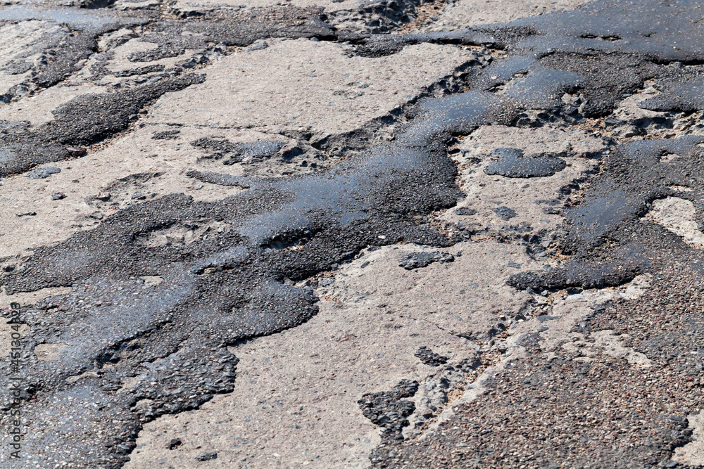 a bad road with poorly repaired potholes and pits a bad road with poorly repaired potholes and pits