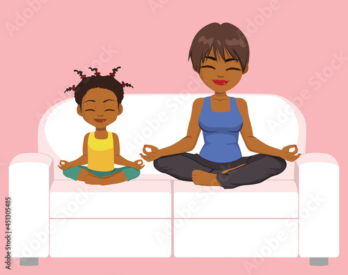 Happy black mother and daughter family meditating and practicing yoga exercises sitting on comfy white couch in lotus position having fun together