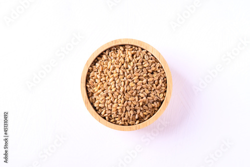 Wheat grain in a wooden bowl on white background, Top view