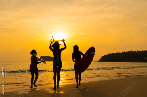 Photography Confidence Asian woman girl friends in swimwear holding surfboard and walking together on the beach at summer sunset