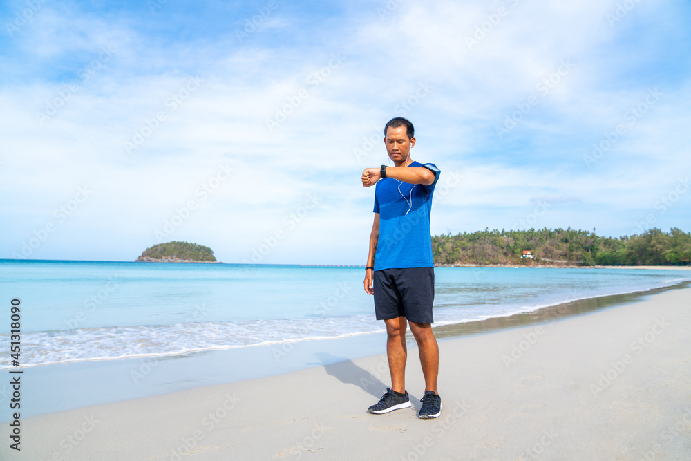 Healthy Asian man in sportswear jogging or running on the beach by the sea in summer morning. Strong athlete male do sport training workout fitness on the beach with listen to music from smartphone Healthy Asian man in sportswear jogging or running on the beach by the sea in summer morning. Strong athlete male do sport training workout fitness on the beach with listen to music from smartphone