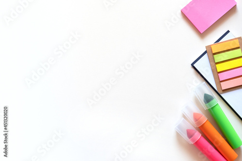 Markers, stickers and notepad on a light white background. Colored office school supplies on the right side. Flatlay with copy space.