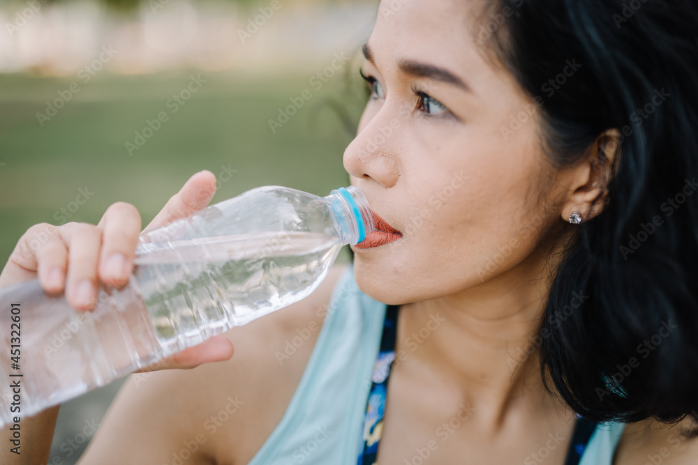 A pretty woman holding a water bottle with a smile. concept of health care and drinking clean water A pretty woman holding a water bottle with a smile. concept of health care and drinking clean water