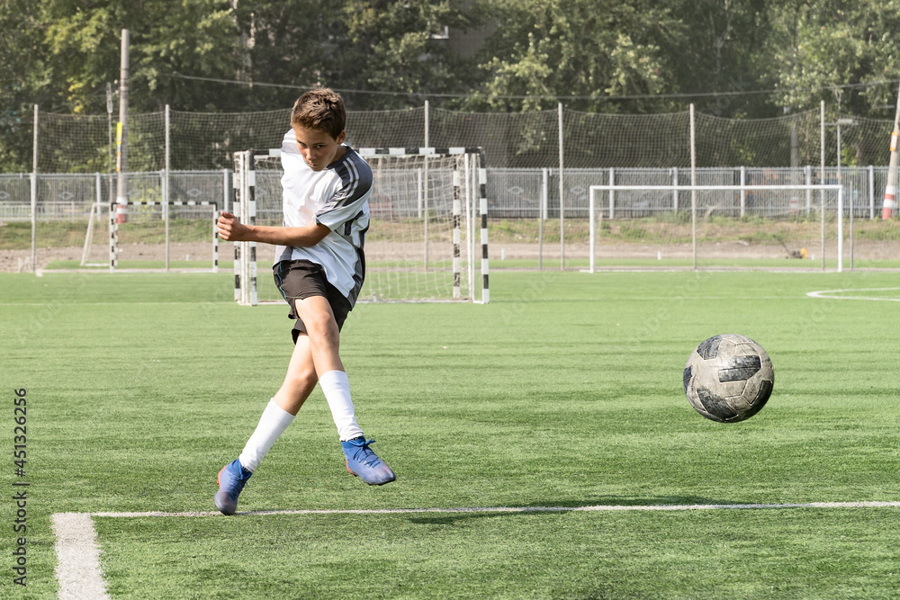 The boy loves to play football, trains with the ball on the artificial turf and scores a goal. The boy plays football The boy loves to play football, trains with the ball on the artificial turf and scores a goal. The boy plays football