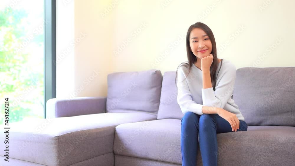 Portrait of Happy Young Satisfied Asian Woman Sitting on Couch in a Family Home Looking at Camera, Full Frame Portrait of Happy Young Satisfied Asian Woman Sitting on Couch in a Family Home Looking at Camera, Full Frame