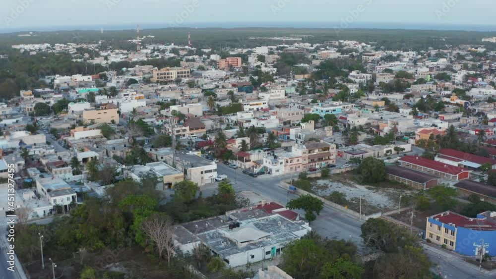 Panoramic slow motion aerial view of vehicles running on road with buildings and trees on a clear sky during morning in the beautiful city Tulum in Mexico Panoramic slow motion aerial view of vehicles running on road with buildings and trees on a clear sky during morning in the beautiful city Tulum in Mexico