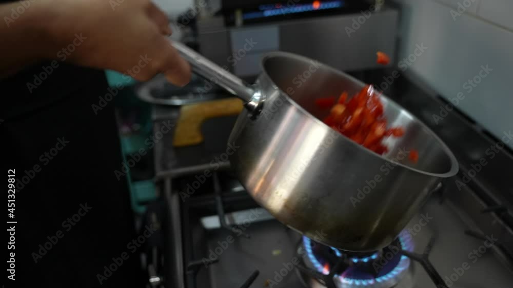 Cooking a delicious dish in a modern kitchen.A chef in a Cafeteria Prepares Dish in pan with Open Flames.He Works in a Modern Kitchen with Different Ingredients Lying Around. Cooking a delicious dish in a modern kitchen.A chef in a Cafeteria Prepares Dish in pan with Open Flames.He Works in a Modern Kitchen with Different Ingredients Lying Around.