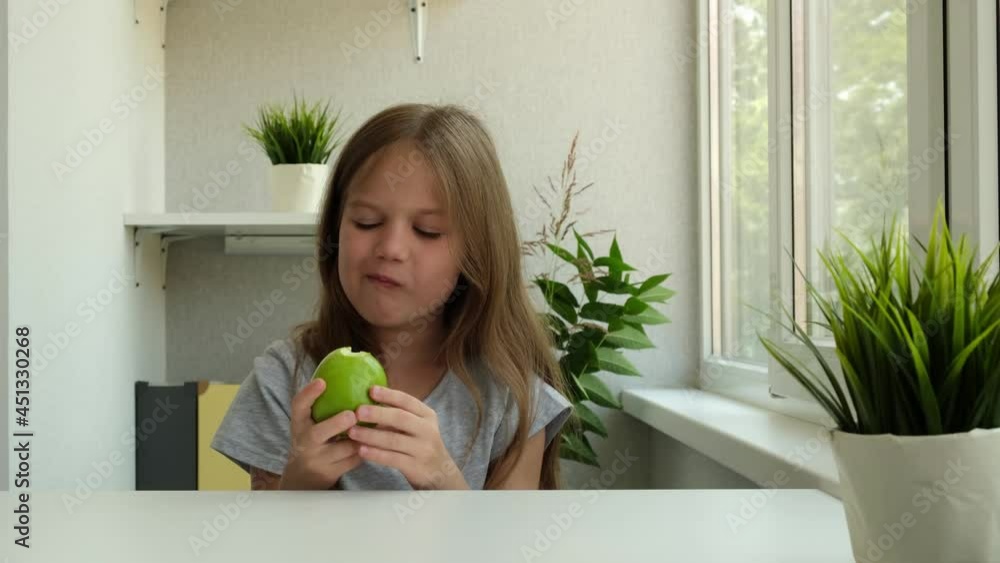 Little girl eating green apple at home. Child with fruit. Concept of healthy lifestyle Little girl eating green apple at home. Child with fruit. Concept of healthy lifestyle