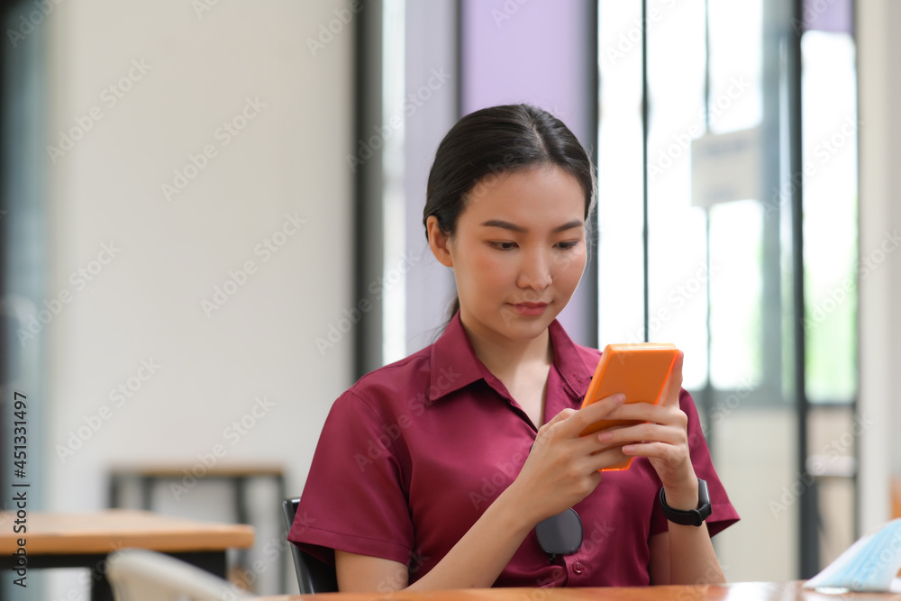 Young Asian woman using smart phone in office room. Young Asian woman using smart phone in office room.