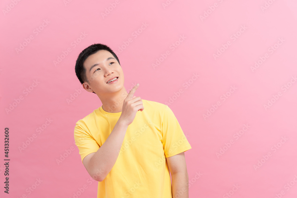 Man pointing finger to the side and presenting a product while smiling on pink background Man pointing finger to the side and presenting a product while smiling on pink background