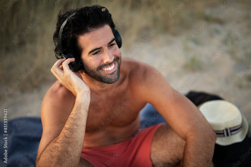 Handsome guy chilling at the beach. Young man listening the music while resting at the beach.. Handsome guy chilling at the beach. Young man listening the music while resting at the beach..